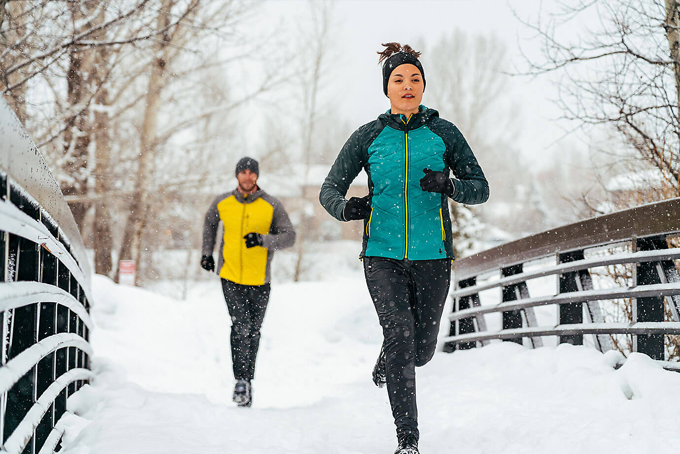 Man and woman running along snowy trail